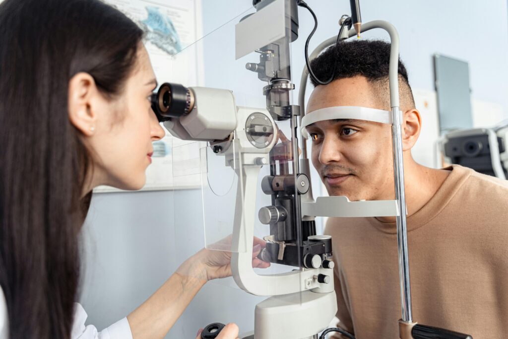 Optometrist examining a patient's eyes with specialized equipment in a clinic setting.